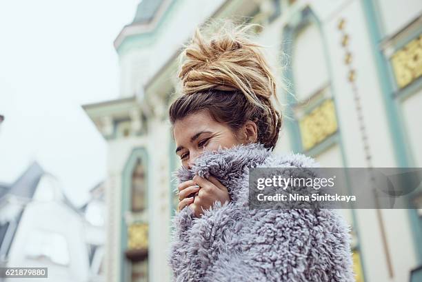 hippie woman wrapping up in fake fur coat outdoors - kunstpelz stock-fotos und bilder