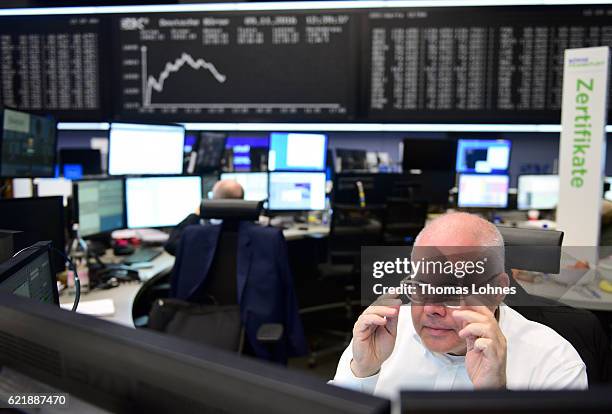 Trader works below the graph showing the day's course of the DAX index at the Frankfurt Stock Exchange on November 9, 2016 in Frankfurt, Germany....