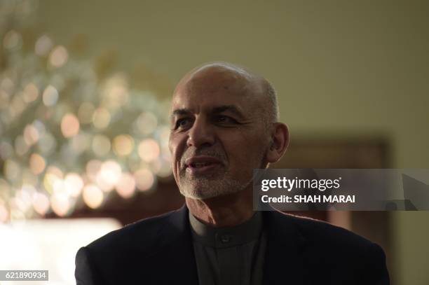 Afghan President Ashraf Ghani looks on as he speaks with Sharbat Gula at the Presidential Palace in Kabul on November 9, 2016. - An Afghan woman...