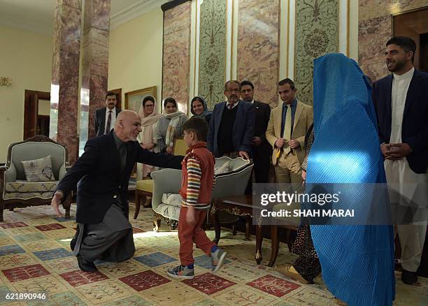 Afghan President Ashraf Ghani greets the son of refugee Sharbat Gula at the Presidential Palace in Kabul on November 9, 2016. An Afghan woman...