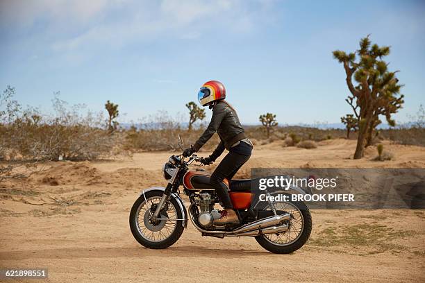young woman riding motorcycle on empty road - crash helmet fotografías e imágenes de stock