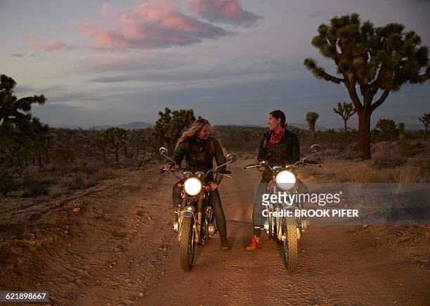 two young women on motorcycles on empty road - brook steppe photos et images de collection