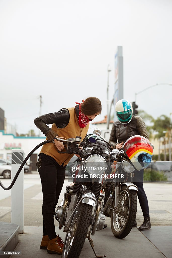 Two young women pumping gas for motorcycle ride