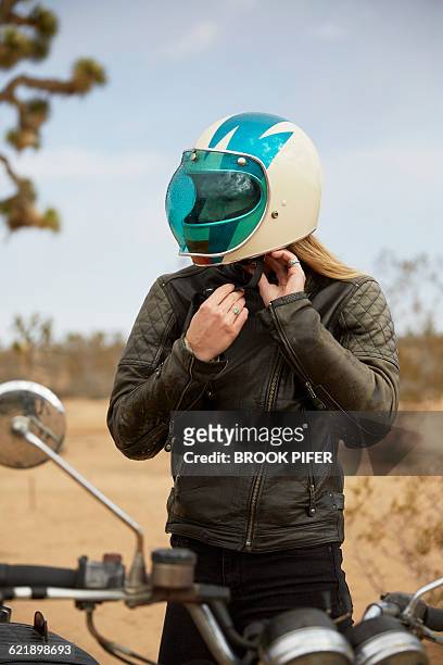 young woman putting on motorcycle helmet - brook steppe photos et images de collection