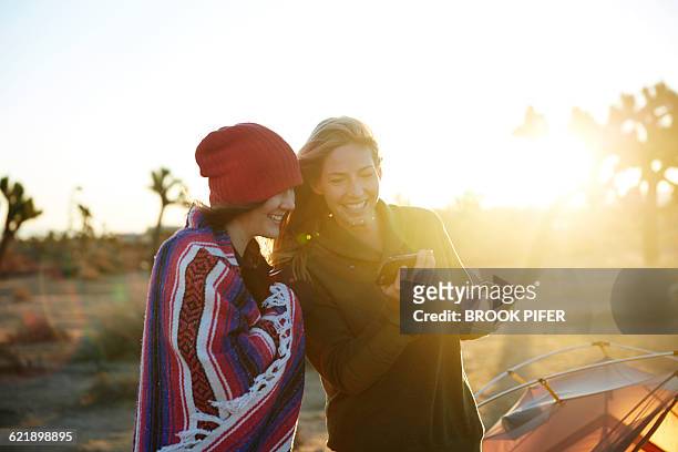 Two young women looking at phone at campsite