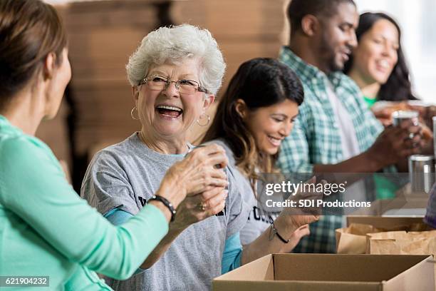 bella allegra anziana volontaria alla banca del cibo - banco alimentare foto e immagini stock