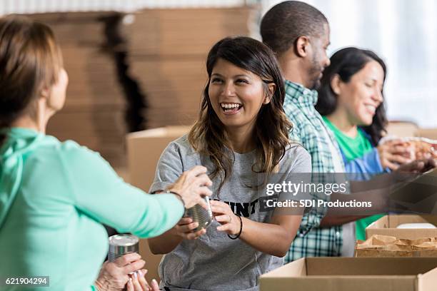 volunteer accepts canned food donation at food drive - ajuda humanitária imagens e fotografias de stock