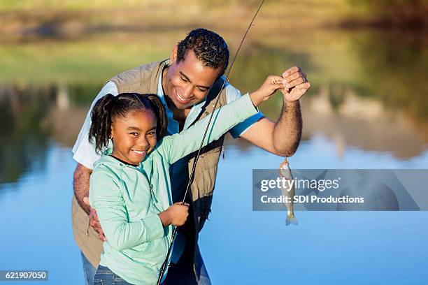 chica orgullosa muestra peces mientras pesca con el abuelo - charca fotografías e imágenes de stock