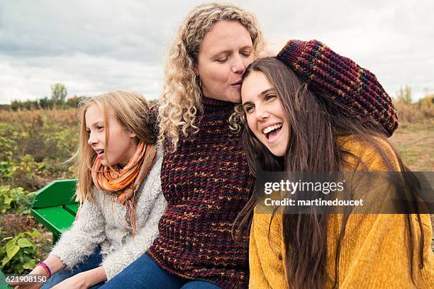 mother kissing teenage daughter strolling in trailer in field. - mature woman daughter stock pictures, royalty-free photos & images