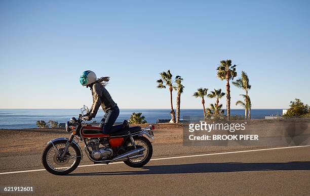 young woman riding motorcycle on empty road - malibu stock pictures, royalty-free photos & images