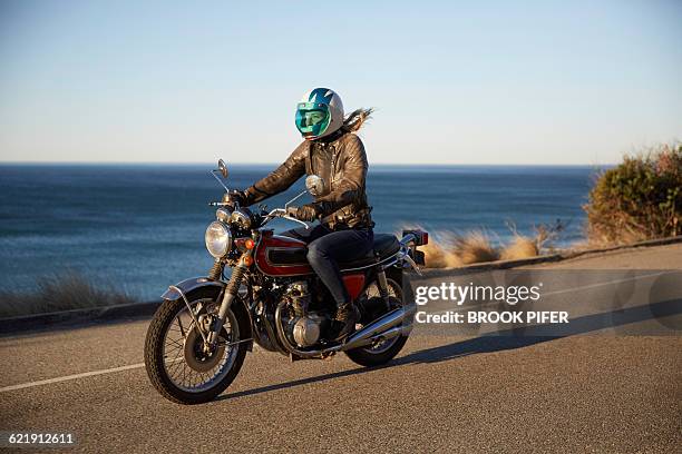 young woman riding motorcycle on empty road - motorbike riding stock pictures, royalty-free photos & images