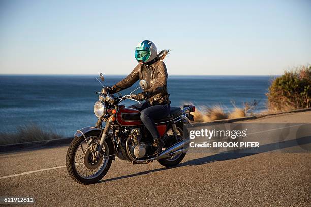 young woman riding motorcycle on empty road - moto imagens e fotografias de stock