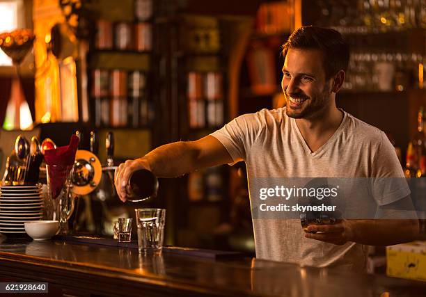 happy bartender at bar counter preparing a cocktail. - cocktail shaker stock pictures, royalty-free photos & images