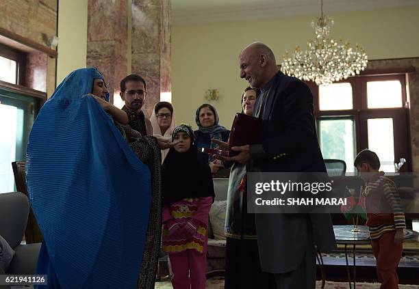 Afghan President Ashraf Ghani presents Afghan refugee Sharbat Gula, , with a key to a new apartment at the Presidential Palace in Kabul on November...