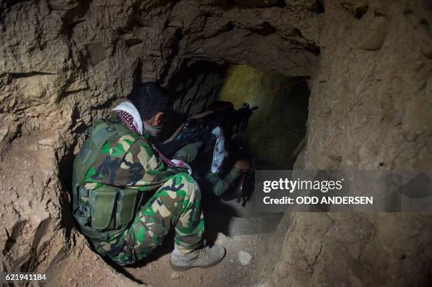 The laser from a Peshmerga fighters assault rifle is seen as they move through an Islamic State jihadist group's tunnel before entering it in Bashiqa...