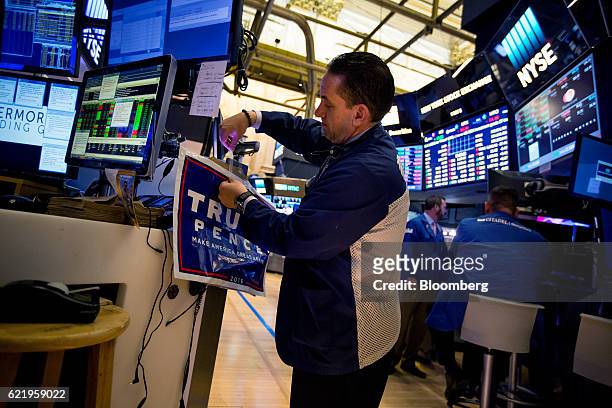Trader tapes a campaign sign for U.S. President-elect Donald Trump and U.S. Vice President-elect Mike Pence to a desk on the floor of the New York...