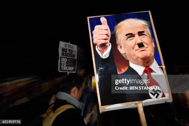 Demonstrator holds a placard showing a picture of US President-elect Donald Trump modified to add a swastika and an Adolf Hitler-style moustache...