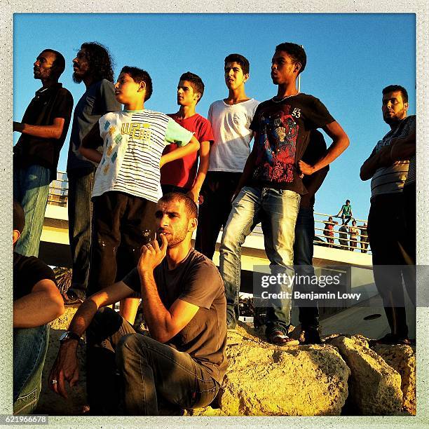 Scores of Libyan men and boys swarm Tripoli's port cornish after a lorry rolled off an overpass and into the sea on the first day of Ramadan in...