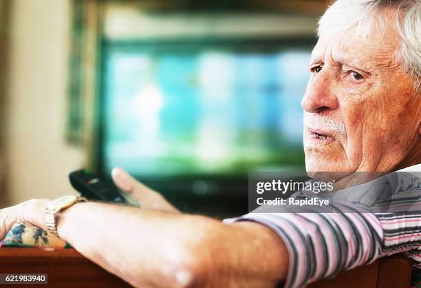 grincheux homme de 90 ans dérangé en regardant la télévision - vieux grincheux photos et images de collection