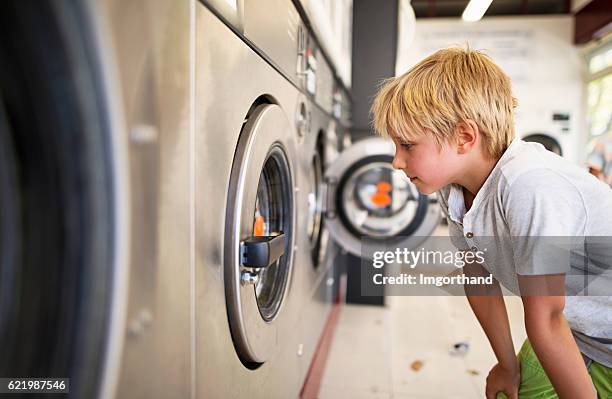 little boy observing working laundromat in self-service laundry - money laundery stock pictures, royalty-free photos & images