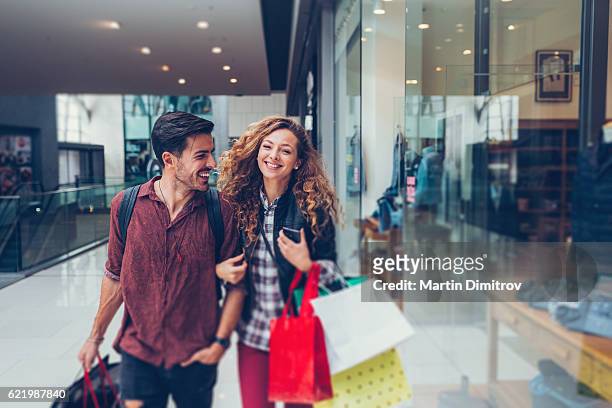 jeune couple faisant du shopping dans le centre commercial - faire les courses photos et images de collection