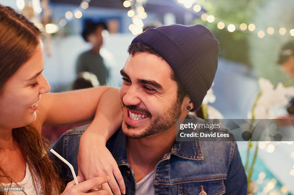 Couple laughing and relaxing at poolside party