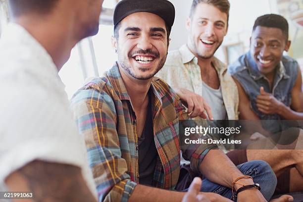 friends laughing and relaxing indoors - male friendship stock pictures, royalty-free photos & images