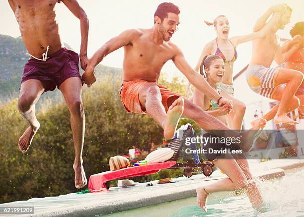 friends jumping into swimming pool at pool party - poolparty stockfoto's en -beelden