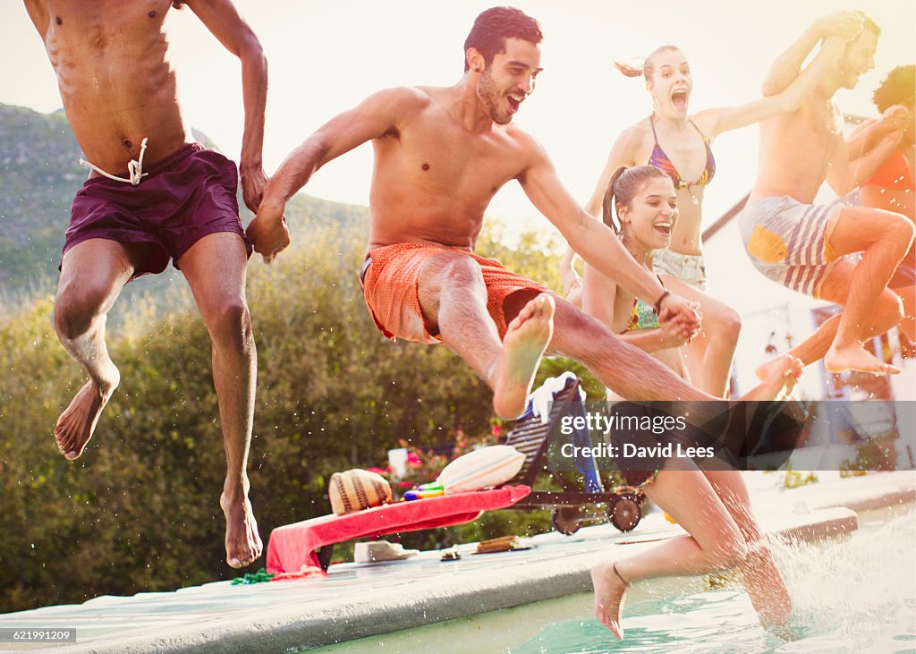 Friends jumping into swimming pool at pool party