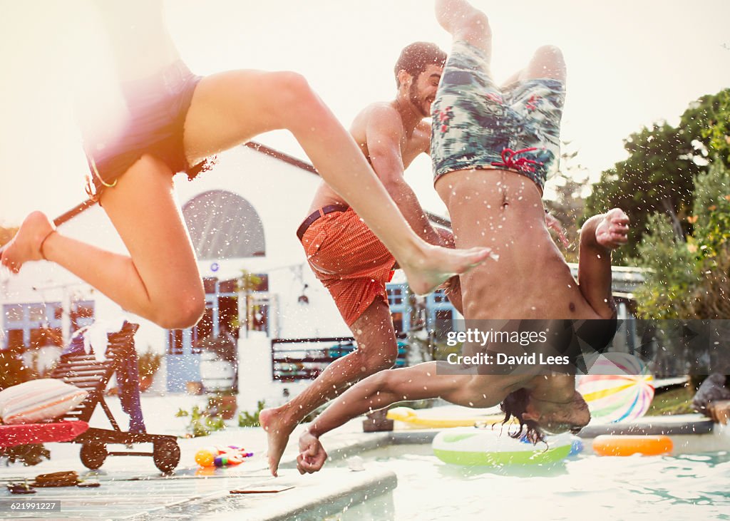 Friends jumping into swimming pool at pool party