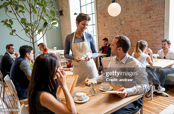 waitress serving people at a restaurant - restaurant server stock pictures, royalty-free photos & images