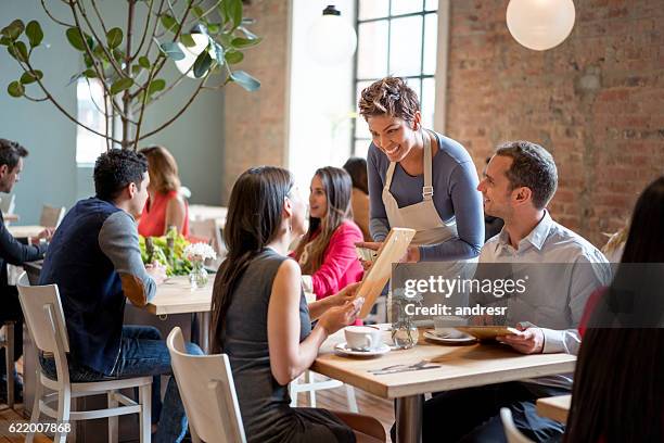 amable camarera que sirve pareja en un restaurante - waitress fotografías e imágenes de stock