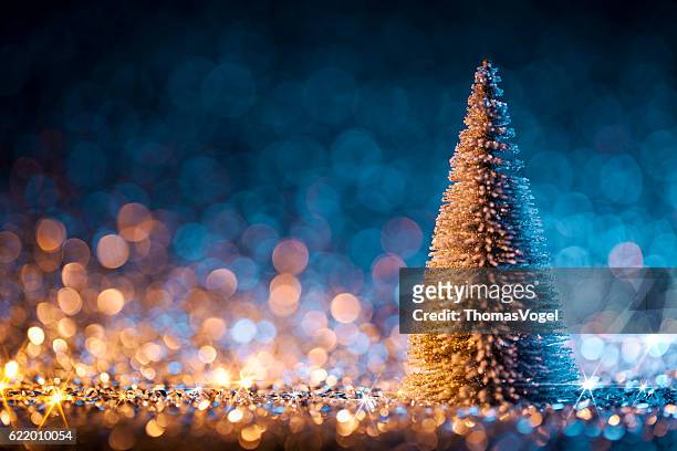 christmas tree on defocused lights. decorations blue gold - blue winter tree stockfoto's en -beelden