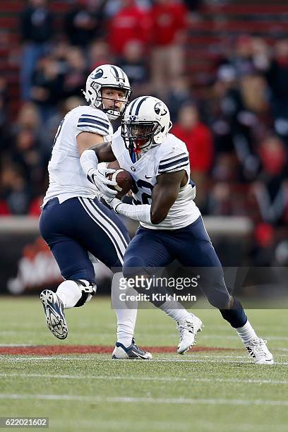 Taysom Hill of the BYU Cougars hands the ball off to Squally Canada of the BYU Cougars during the game against the Cincinnati Bearcats at Nippert...