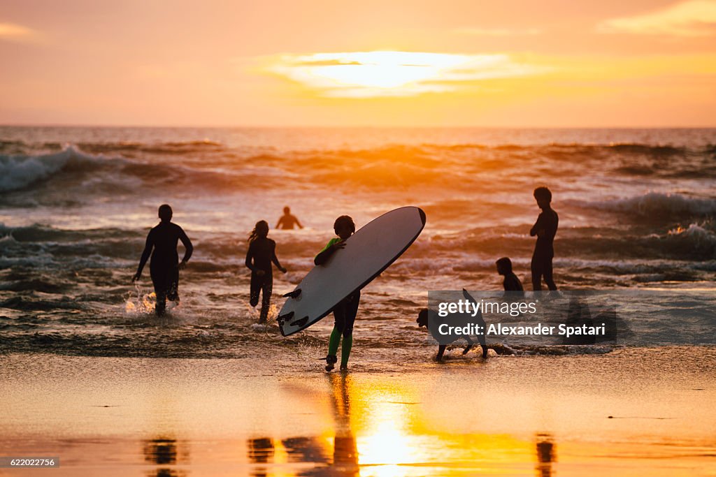 Silhouettes of friends playing in waves on the beach