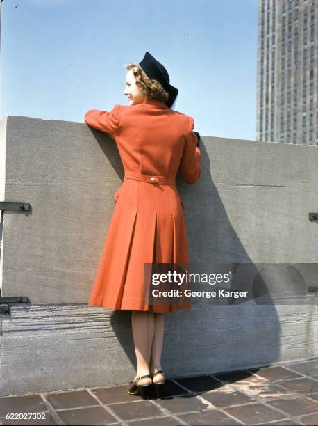 Woman modeling a long, pleated red coat, 1941.