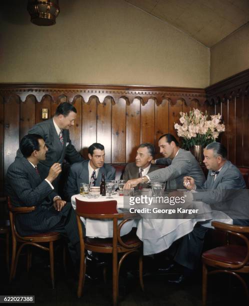 Hank Greenberg and Bob Feller with a group of men at a table at Toots Shor's Restaurant in New York City.