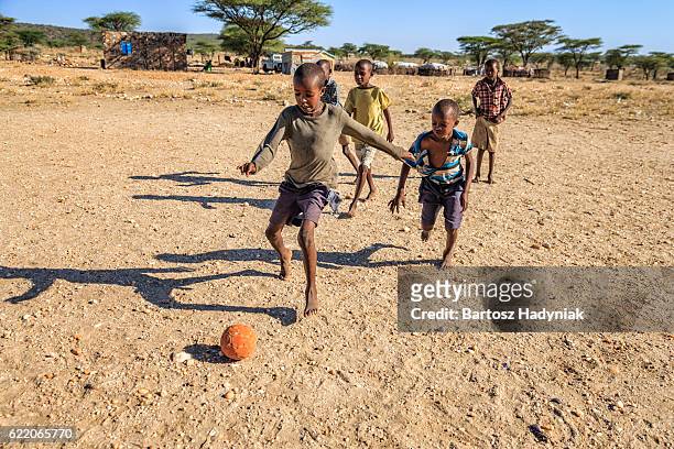 barfuß afrikanische kinder spielen fußball im dorf, ostafrika - africa game stock-fotos und bilder