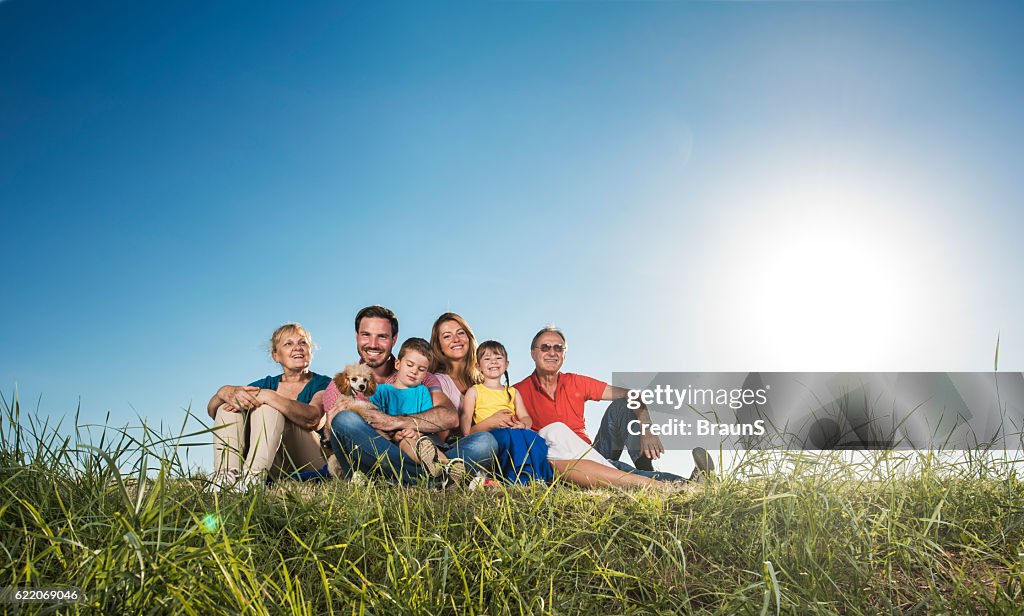 Smiling extended family enjoying in sunny day on grass.