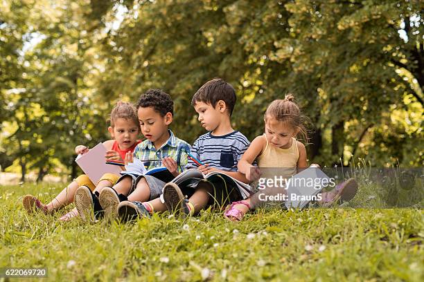 group of cute kids writing in notebooks at the park. - report fun stock pictures, royalty-free photos & images