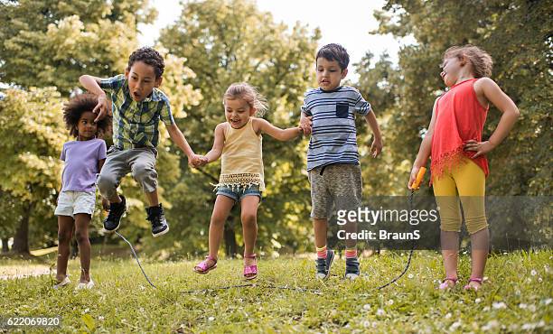 grupo de niños juguetón divirtiéndose mientras saltan la cuerda de salto. - dar brincos fotografías e imágenes de stock