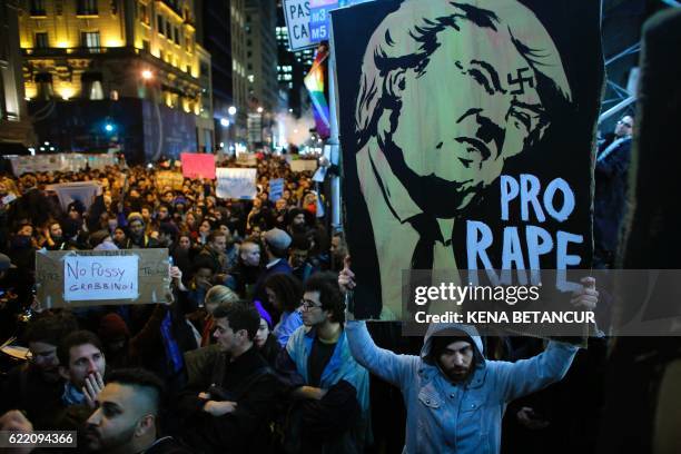 Man holds a poster as she takes part in a protest against President-elect Donald Trump in New York City on November 9, 2016.