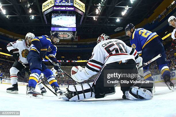 Corey Crawford of the Chicago Blackhawks makes a save against Patrik Berglund and Alexander Steen of the St. Louis Blues at the Scottrade Center on...