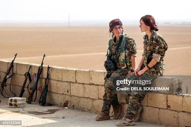 Shirin and Kazîwar , members of the Kurdish female Women's Protection Units engage in conversation next to Kalashnikov assault rifles on a house...