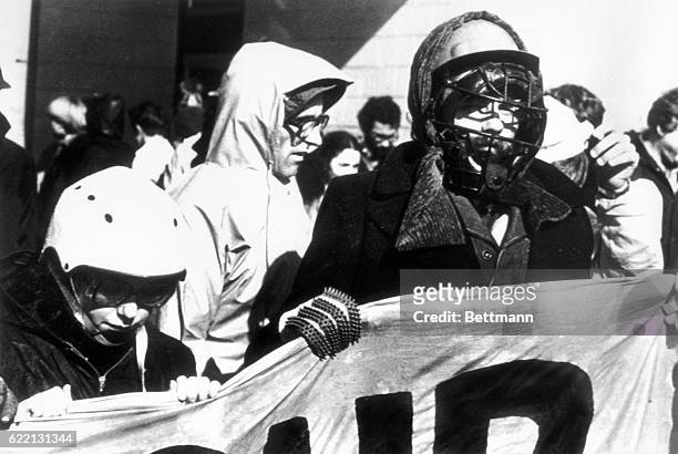 Pauline McKay, Chairperson of HART marches behind a banner with anti-apartheid demonstrator wearing baseball helmet and cricket gloves towards rugby...