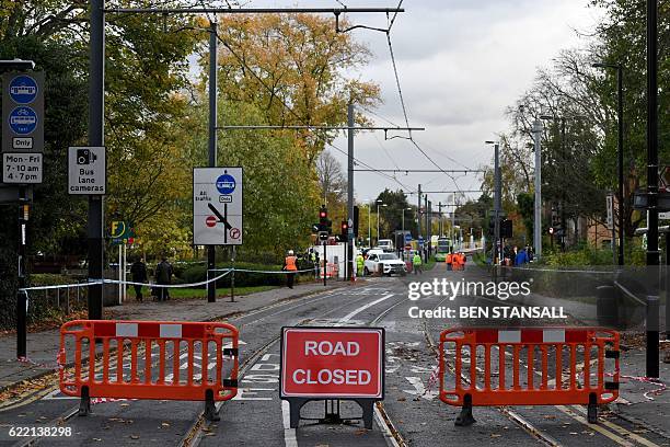 Workers are seen at a tram stop where the road remains closed near the scene of a derailed tram in Croydon, south of London, on November 10, 2016. At...