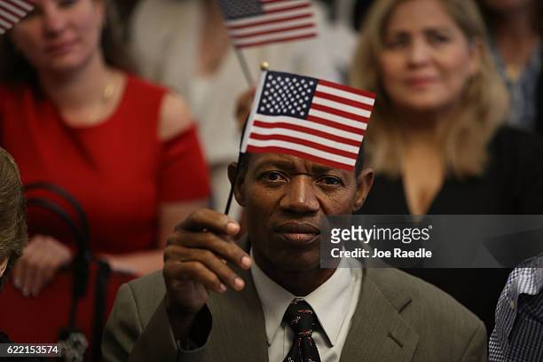 Marckingson Lambert holds an American flag as he becomes an American citizen during a ceremony at the U.S. Citizenship and Immigration Service's...