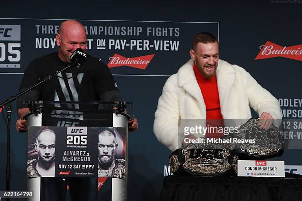 Conor McGregor of Ireland takes Eddie Alvarez's lightweight belt during the UFC 205 press conference at The Theater at Madison Square Garden on...