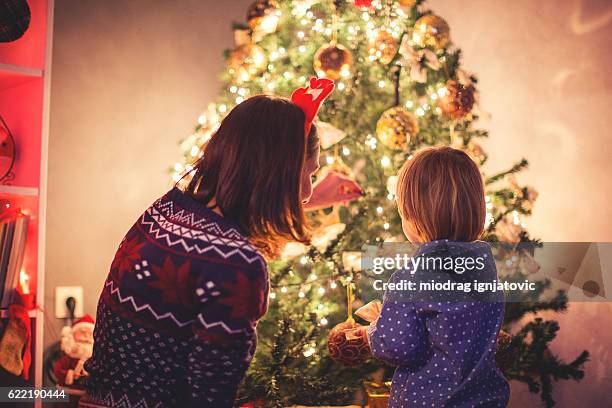 mother decorating christmas tree with her son - decorating-the-christmas-tree stock pictures, royalty-free photos & images
