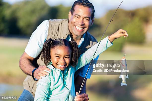 proud girl shows of fish with granddad - kids fishing stock pictures, royalty-free photos & images